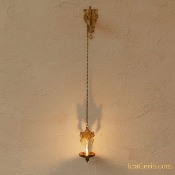 Antique brass diya featuring shankh and chakra, a spiritual wall hanging oil lamp.