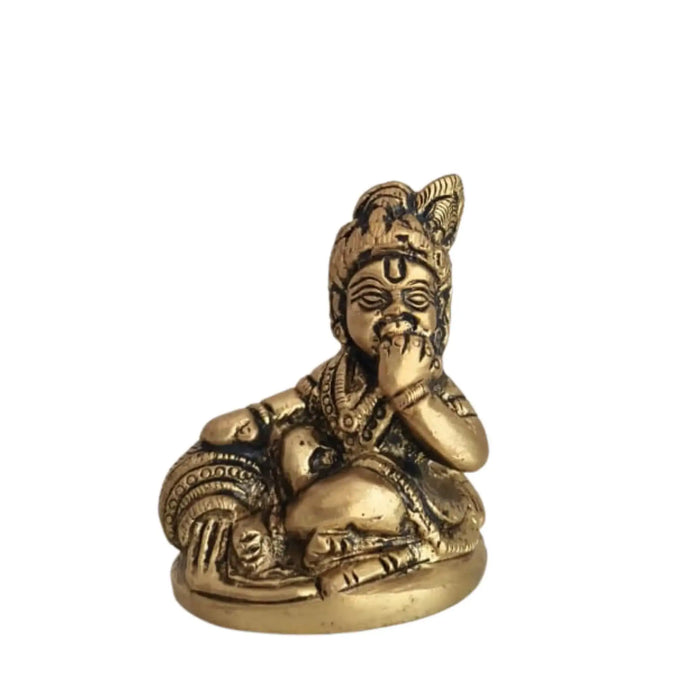 Brass Bal Krishna idol holding a butter ball, a classic devotional art piece.
