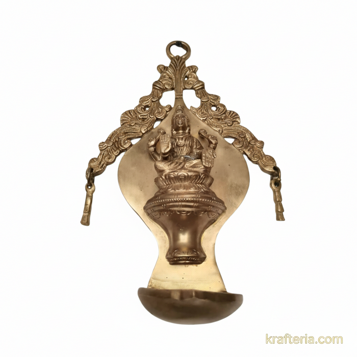 Ornate brass Lakshmi diya wall hanging, traditional oil lamp with arch.