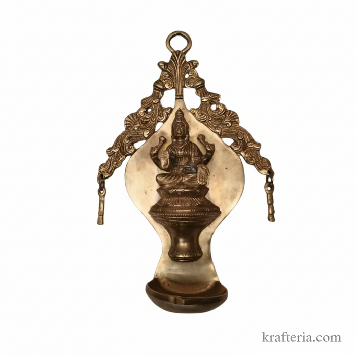 Brass Lakshmi diya wall hanging with ornate arch.