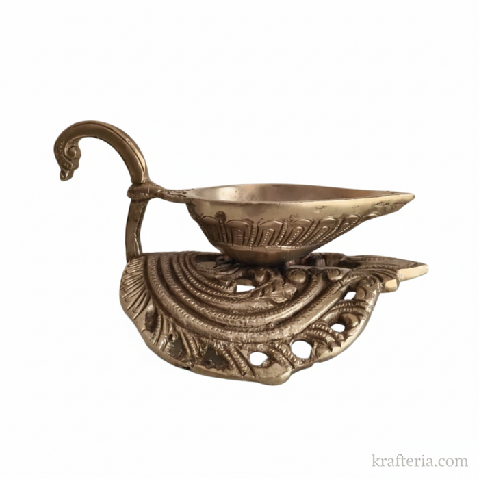 A brass diya lamp with a swan handle, a traditional oil lamp for rituals.