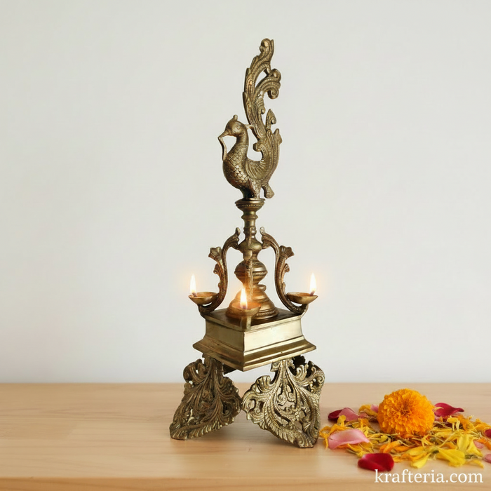Ornate brass peacock diya, a 4-wick standing oil lamp, decorative and functional.