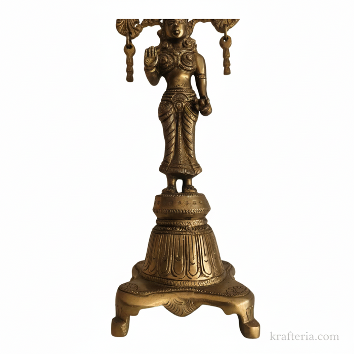 Intricate brass Radha goddess idol with ornate prabhavali backdrop.