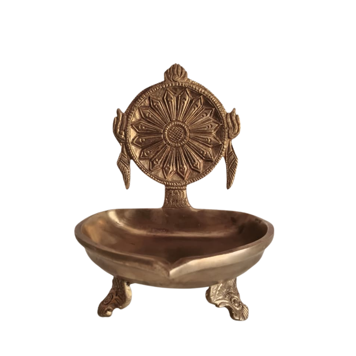 Brass shankh chakra diya set on a table, showcasing spiritual oil lamps and decor.