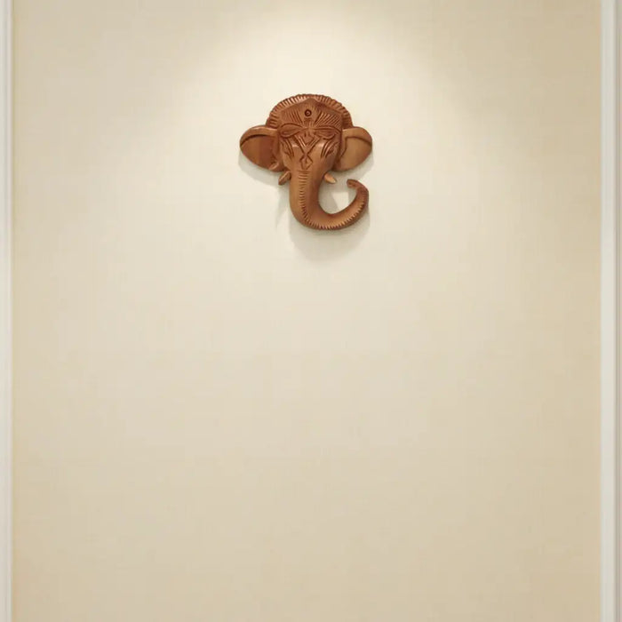 Hand-carved wooden Ganesha elephant head wall hanging with intricate detailing for home temple décor