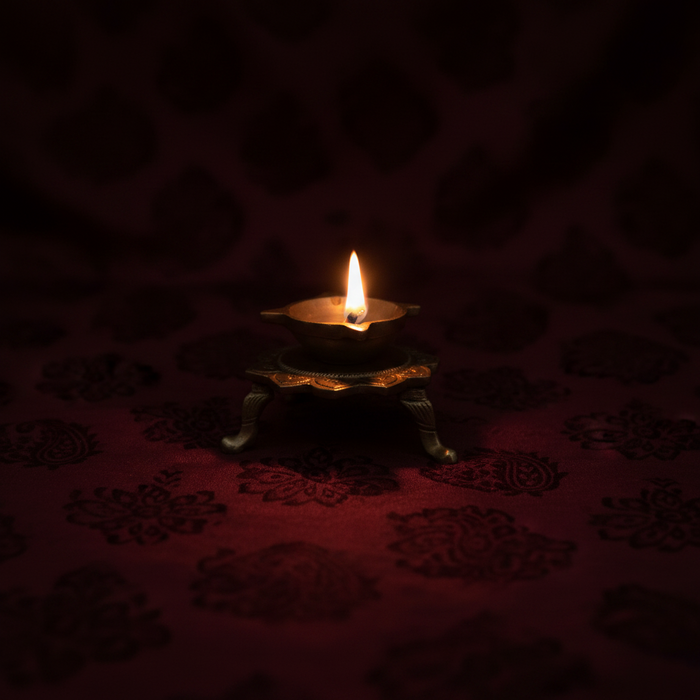 Handcrafted brass lotus diya tabletop oil lamp with ornamental legs.