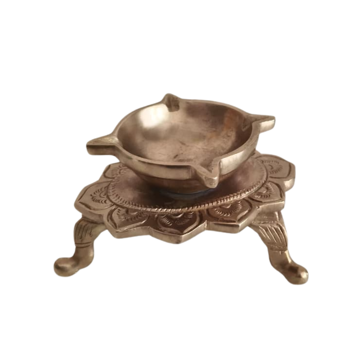 Ornate brass lotus diya with ornamental legs, a traditional tabletop oil lamp.
