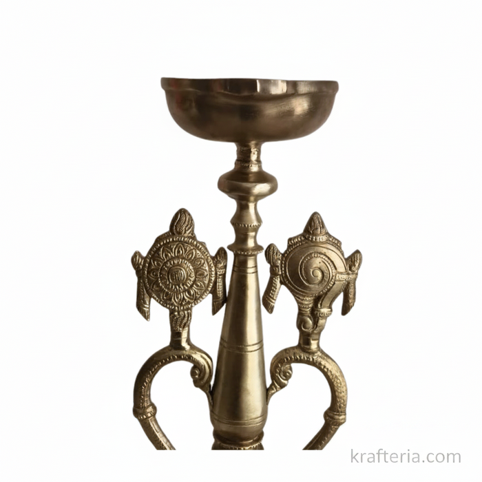 Sacred brass Vishnu lamp with shankh and chakra on a pedestal, used as an altar diya.
