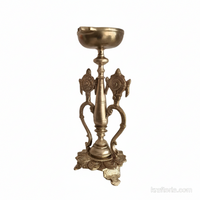 Sacred brass Vishnu lamp with shankh and chakra details on a pedestal.