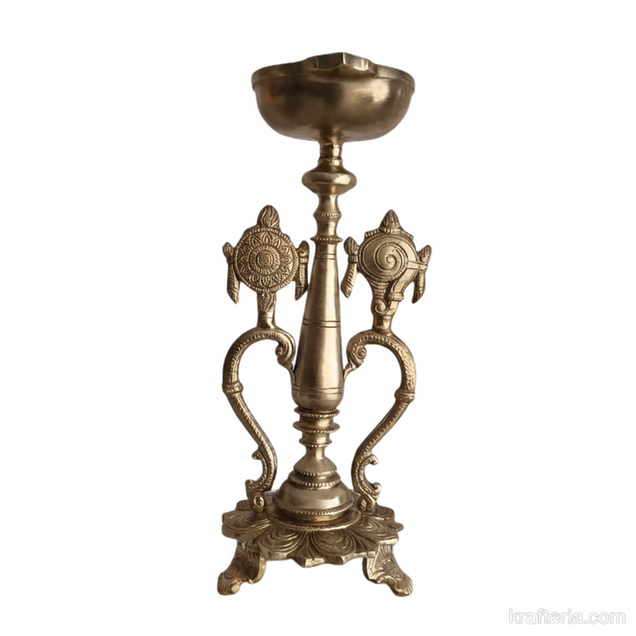 Sacred brass Vishnu lamp with ornate shankh and chakra details on a pedestal.