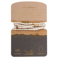 Scout Curated Wears White Lava Stone Wrap bracelet necklace featuring natural white lava gemstones with gold accents and a Stone of Strength meaning card.